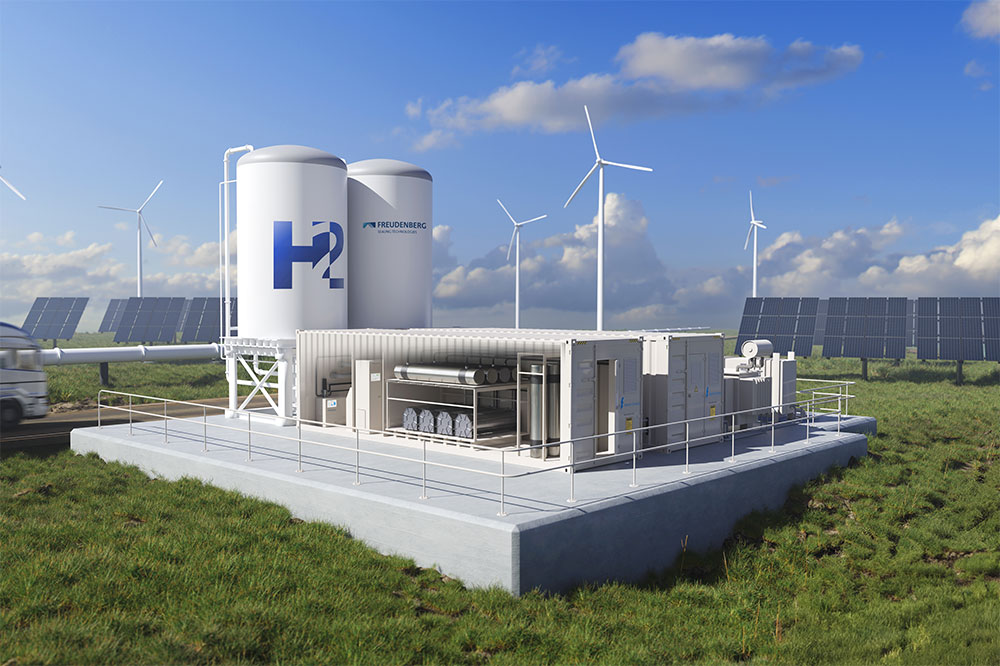 A hydrogen production facility with storage tanks, wind turbines, solar panels, and a truck in a grassy landscape under a partly cloudy sky.