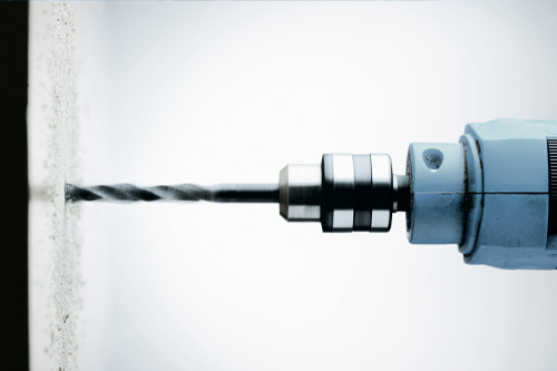 Close up of a drill head drilling a hole in the wall