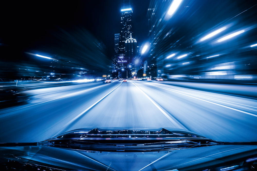 View from car back window: illuminated street in a city at night