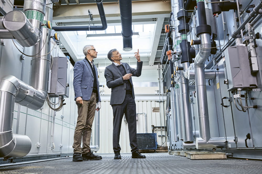 Two men are looking at compressors in a factory.