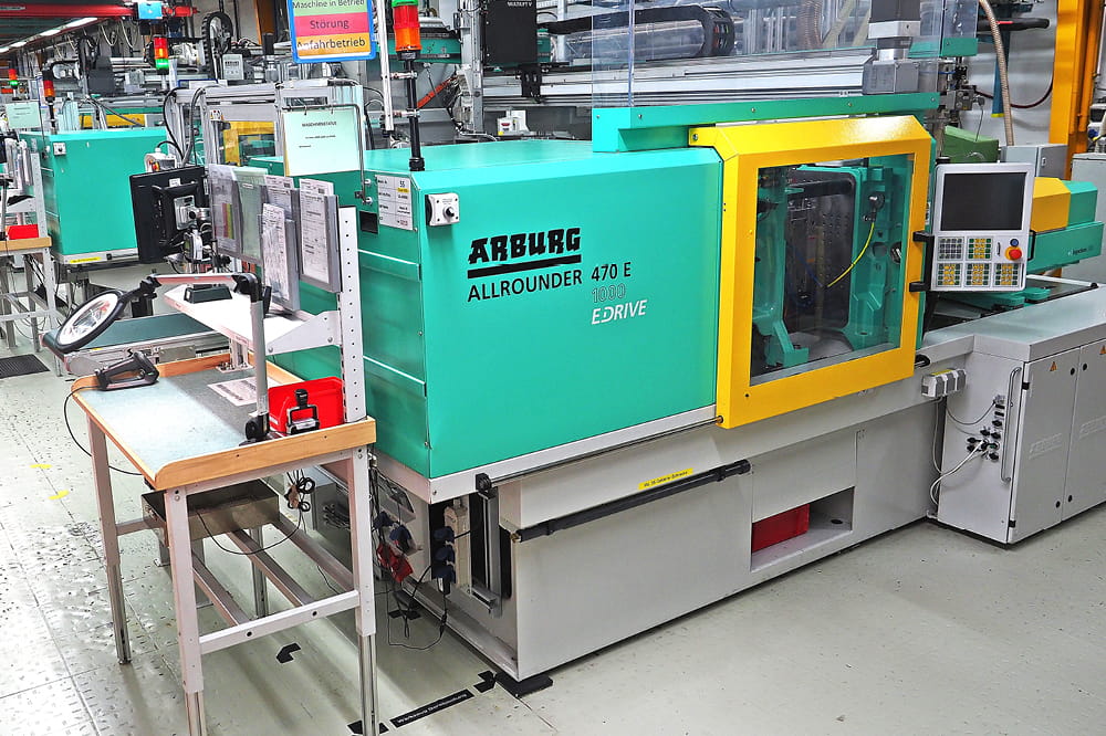 A green machine inside a factory with the inscription Arburg Allrounder 470 E