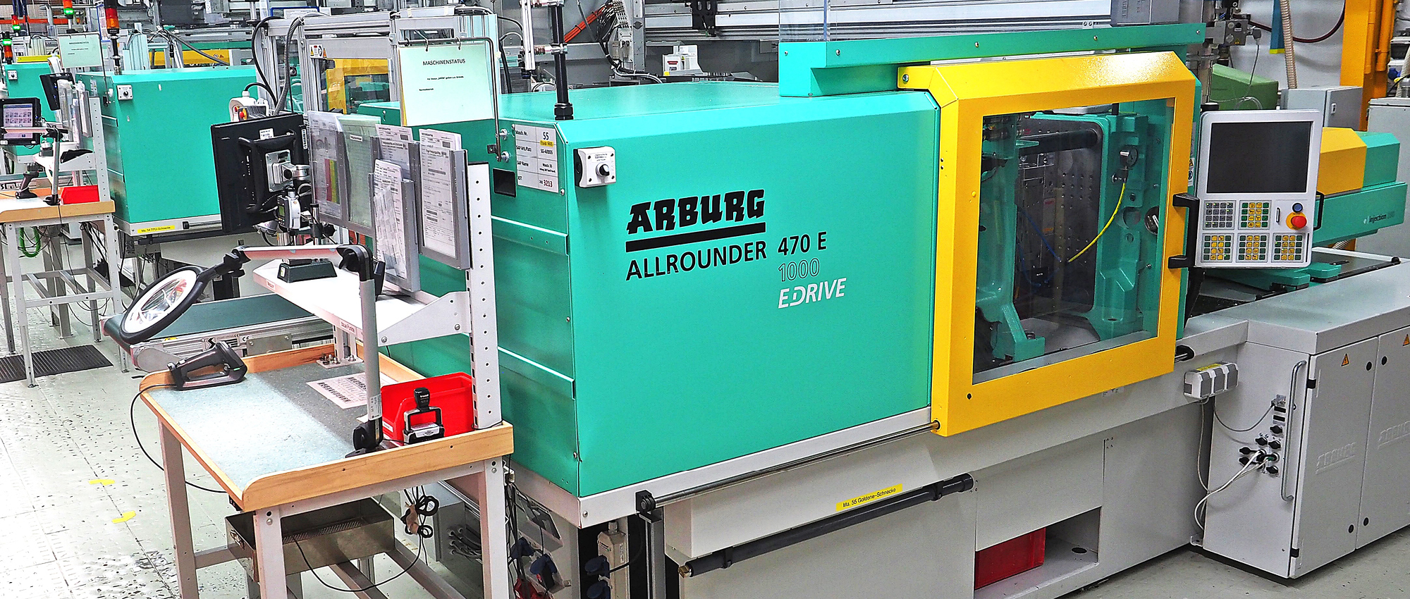A green machine inside a factory with the inscription Arburg Allrounder 470 E