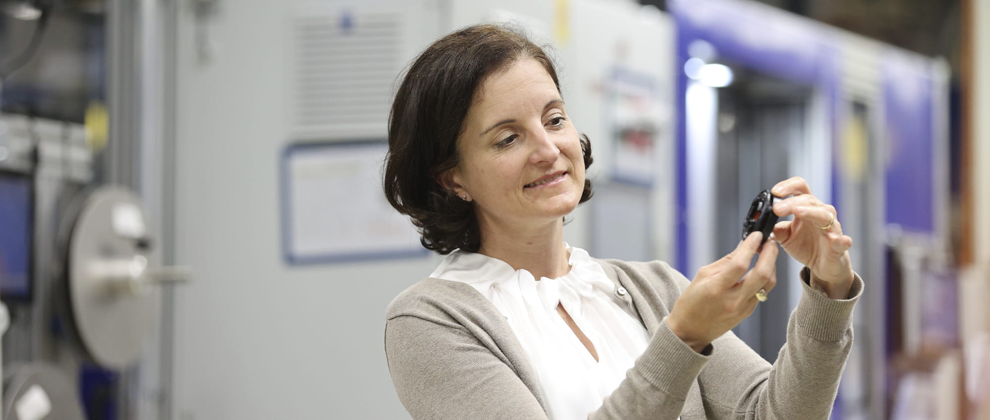 Tanja Heislitz, Technical Director e-mobility bei Freudenberg Sealing Technologies, hält ein Kunststoffteil DIAvent in den Händen und betrachtet es.