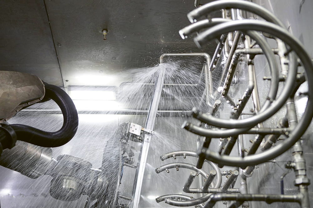Roboter wird in einer Waschanlage mit Wasser bespritzt. Copyright: KUKA Group