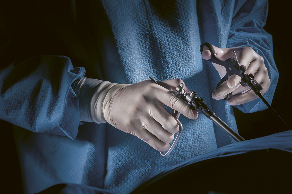 Nahaufnahme von zwei Händen in Handschuhen, die Operationswerkzeug.