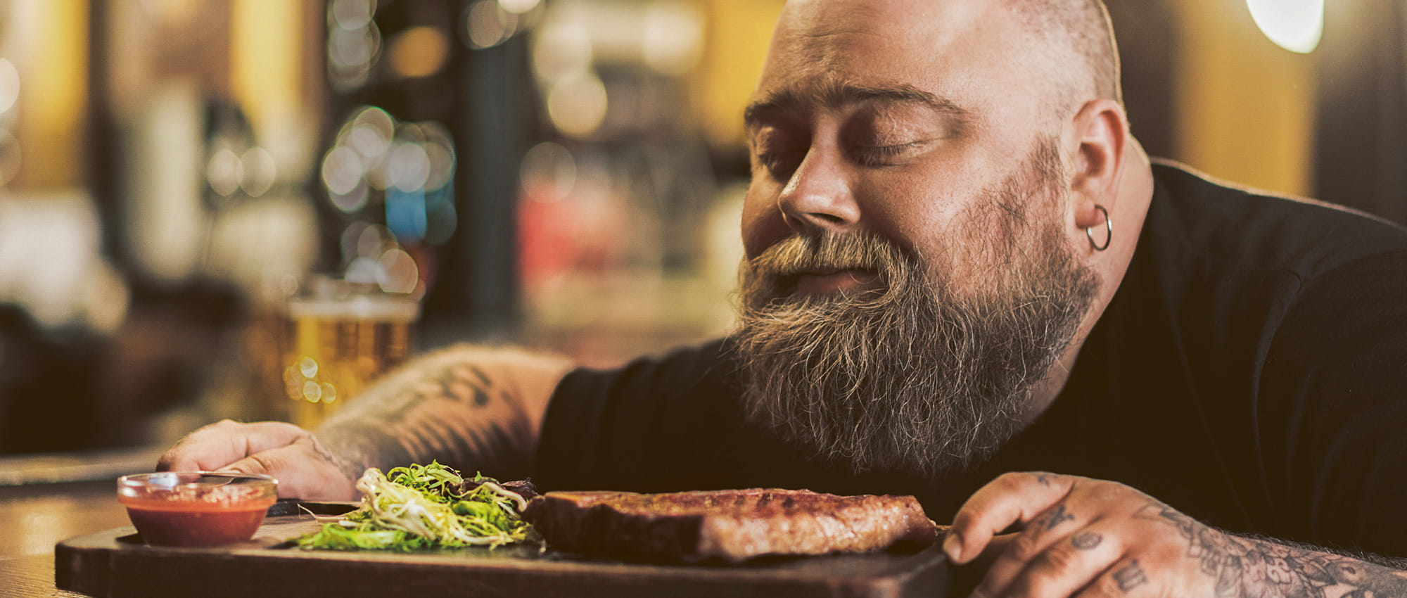 Ein bärtiger Mann riecht mit geschlossenen Augen an einem Teller mit Essen. Copyright: iStock: YakobchukOlena