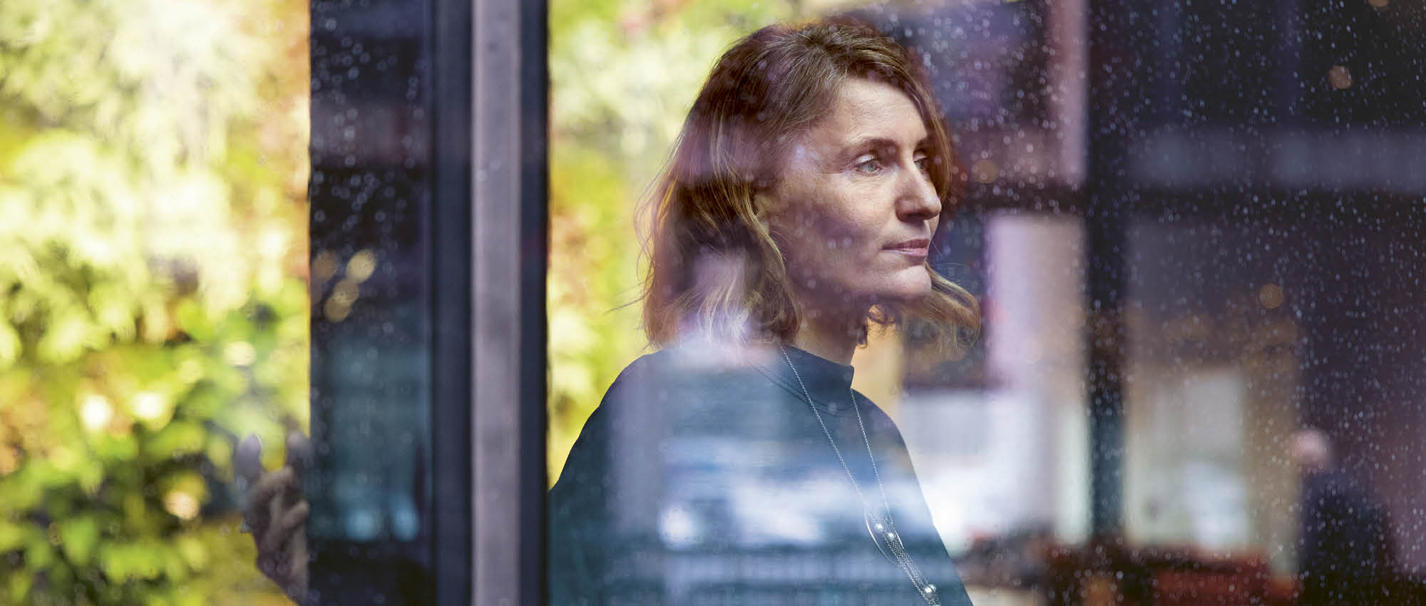 Porträt einer Frau die aus einem Fenster schaut.