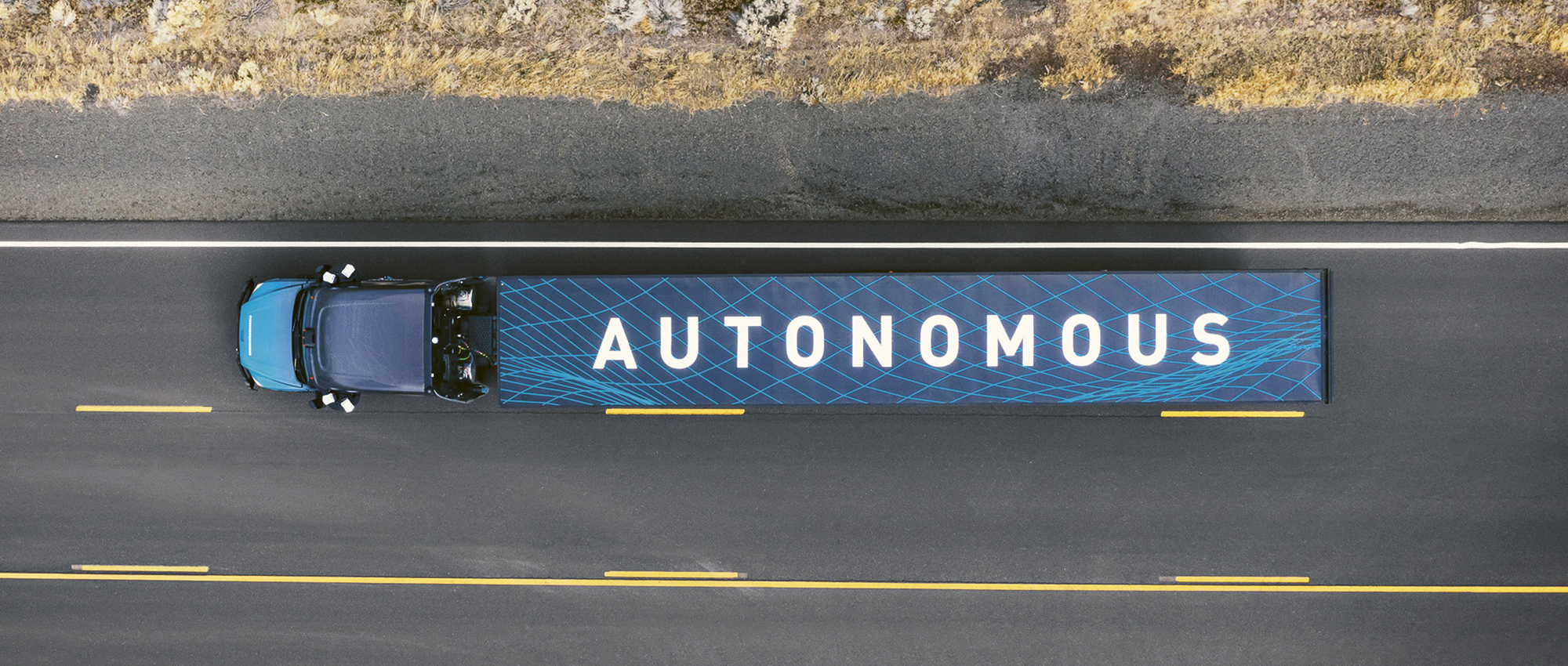 Ein LKW mit der Aufschrift Autonomous fährt auf einer Straße. 