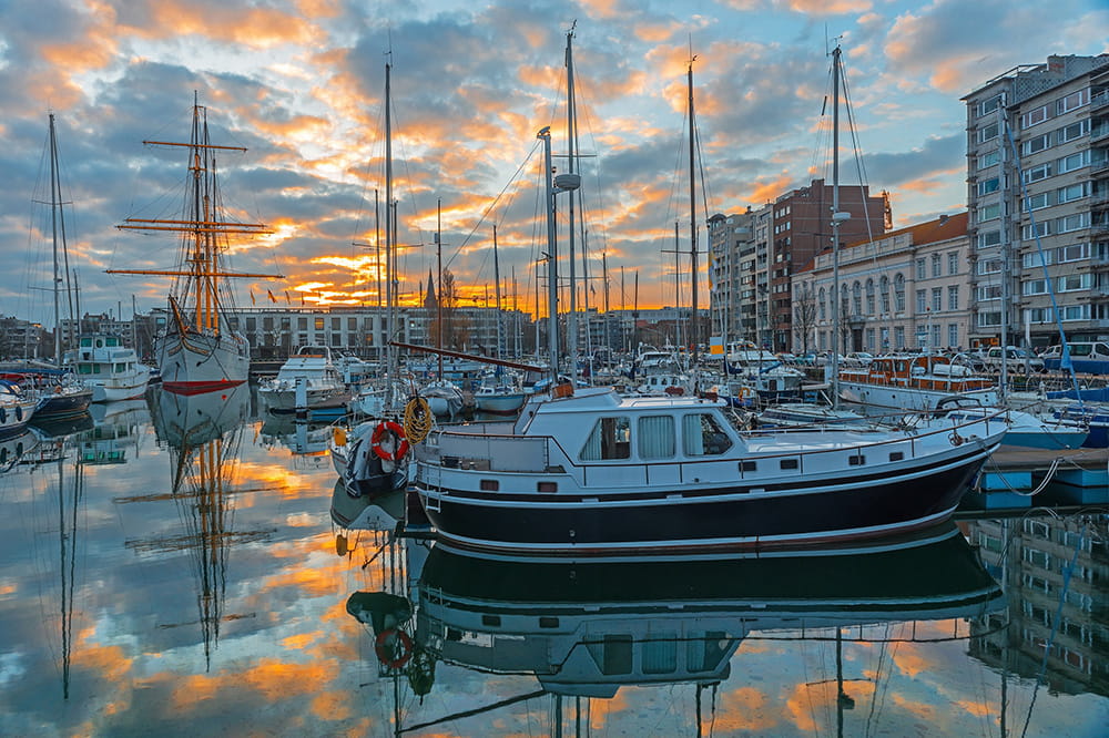 Hafen bei Sonnenuntergang mit Booten, die sich auf dem ruhigen Wasser spiegeln.