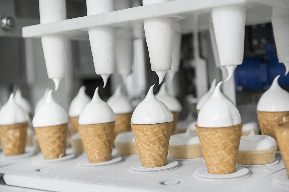 Automatisierter Befüllungsprozess von Eiswaffeln in einer Lebensmittelproduktionsanlage.